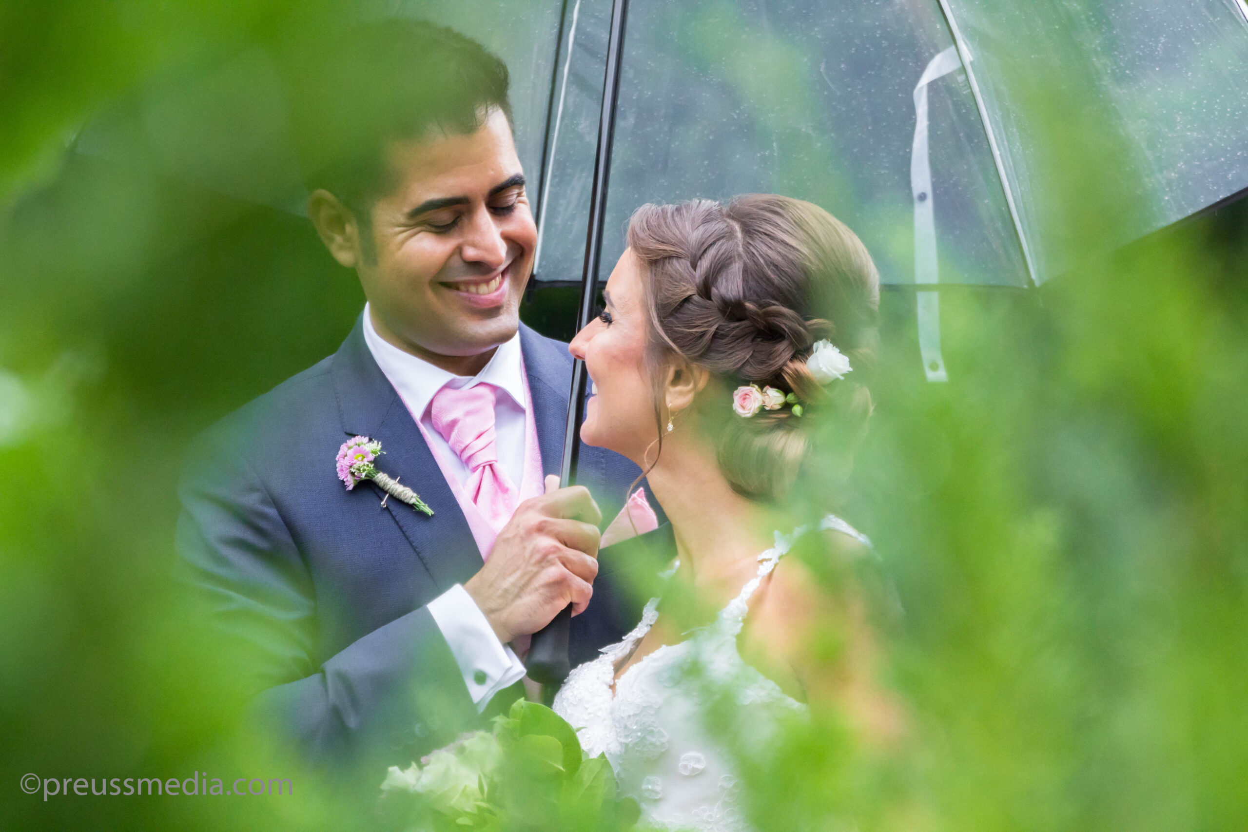 Hochzeitsfotograf Berlin Brandenburg - Brautpaar lächelt sich glücklich an. Steht unter einem durchsichtigen Regenschirm.